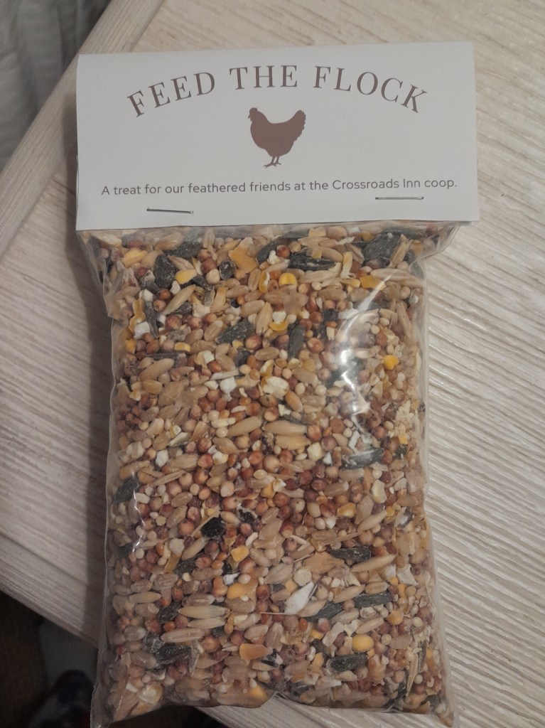Packet of chicken feed with "Feed the Flock, A Treat for our feathered friends at the Crossroads Inn Coop" written on the top.